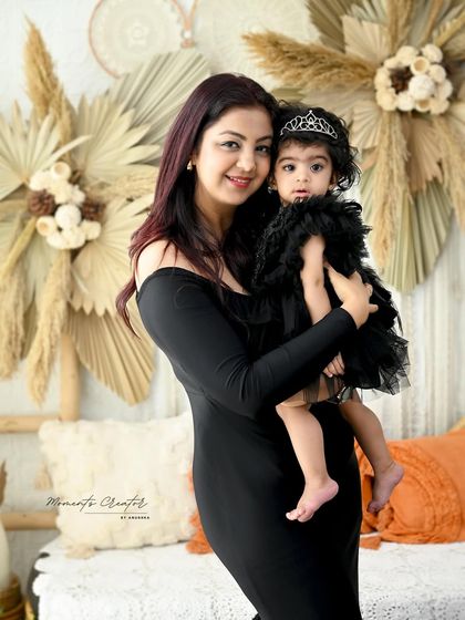 A sweet mother-daughter portrait. The mother holds her little girl, who is wearing an adorable tiara, creating a precious memory of her first year.