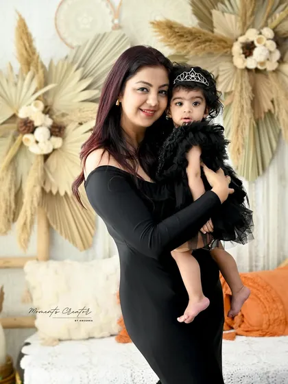 A sweet mother-daughter portrait. The mother holds her little girl, who is wearing an adorable tiara, creating a precious memory of her first year.