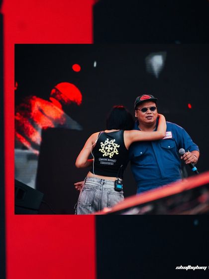 A candid moment of camaraderie between Reble and Kim the Beloved on the Rolling Loud stage. This photo shows the personal interactions that happen during a live set.
