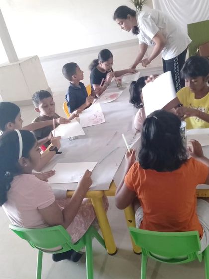 An instructor guides a group of attentive children during a painting session at our summer camp. We keep our groups small to ensure every child gets personalized attention.