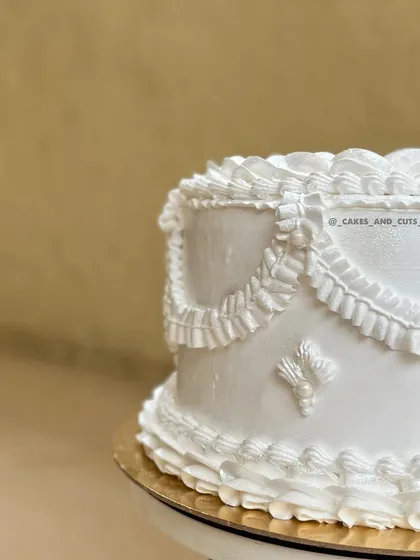 The beauty is in the details. This close-up shows the delicate and precise buttercream piping work that defines a vintage-style cake. We dedicate sessions to mastering different piping nozzles and techniques to create these timeless ruffle and swag effects.