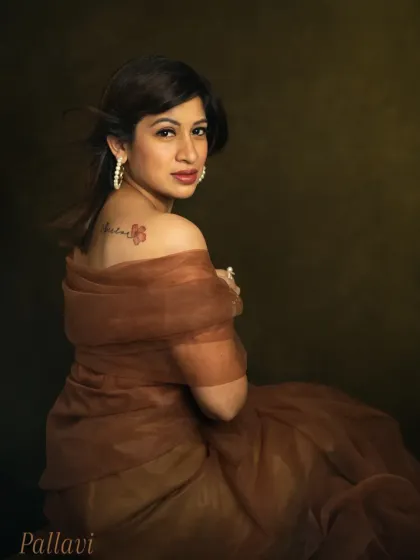 A portrait that reveals a personal story. Pallavi looks over her shoulder, showcasing the meaningful tattoo on her back. The soft lighting and rich colors create an intimate and powerful image that speaks of her journey and resilience.