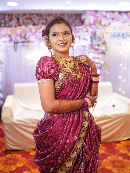 The rich texture of the Banarasi-style magenta saree paired with heavy gold necklaces creates a timeless Maharashtrian bridal look.