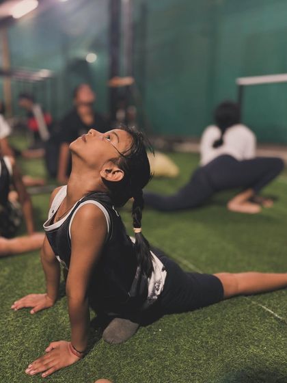 A young athlete demonstrates a pigeon pose (Eka Pada Rajakapotasana), a powerful hip-opening stretch that is fundamental for overall mobility.