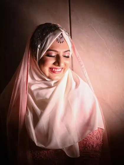 The bride's radiant smile, captured in a moment of pure happiness during her engagement. The soft lighting highlights her joy and the delicate details of her hijabi bridal look.