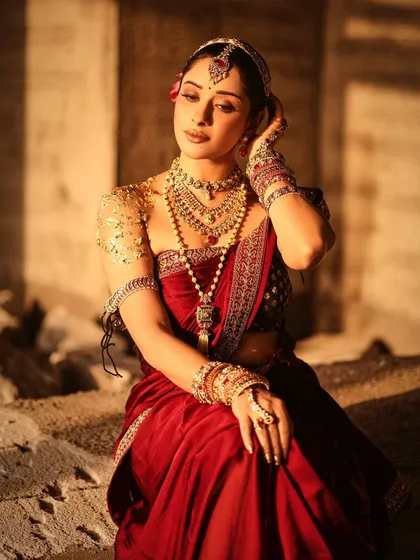 A regal, seated portrait of Nyra Banerjee. The focus here is on the elaborate jewelry, including the maang tikka, choker, and bangles, which are essential elements of our traditional styling.