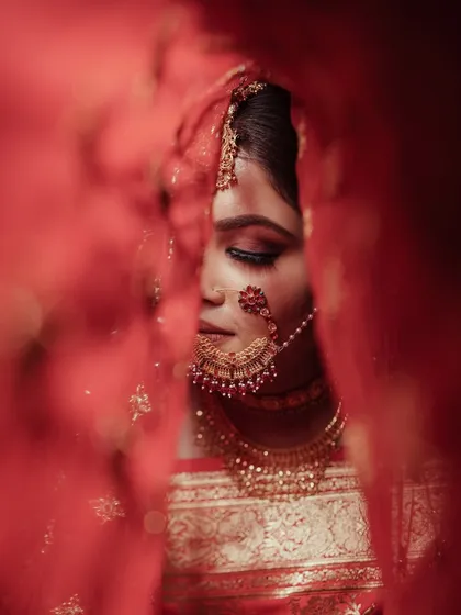 A bridal portrait is more than a photo; it's a story. Here, we created an artistic and intimate moment with our bride Kriti, using her vibrant red veil to frame her serene expression just before the ceremony began.