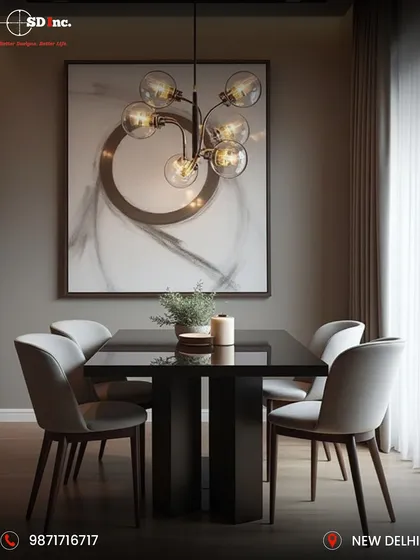 A modern and moody dining area with a sleek black table and light grey upholstered chairs. The space is defined by a dramatic globe chandelier and abstract art, creating a sophisticated ambiance for intimate dinners.