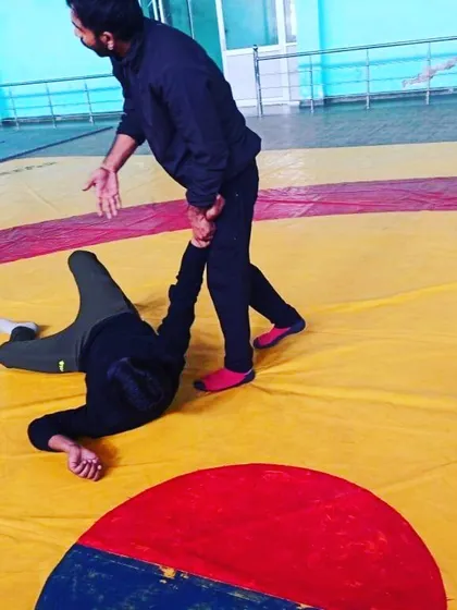 Ground control is essential. This image shows a wrestling drill where one student learns how to control an opponent on the mat.
