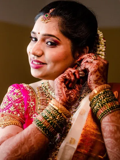 A close-up of the bride getting ready. You can see the details of her henna, the texture of her saree, and the carefully applied makeup that brings her whole Muhurtham look together.