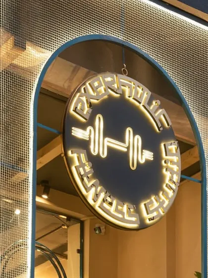 The illuminated studio logo is a beacon for our fitness community. It represents our commitment to strength, wellness, and the energy we cultivate here.