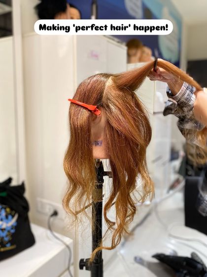 A student sections and prepares a mannequin's hair for an intricate updo, showing the foundational steps required for a stable and beautiful style.