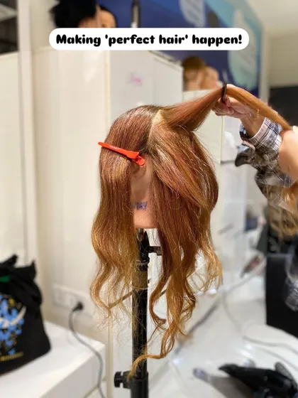 The process of creating perfect curls. A student sections and styles hair on a mannequin, practicing the techniques taught in our hairstyling program.