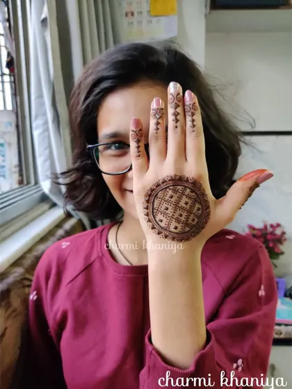 A unique mandala design with a checkered pattern inside. The simple finger details keep the focus on the intricate circle, and the client's pose is just adorable!
