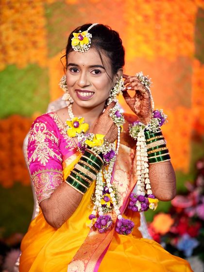 This bride is adjusting her floral earrings. The hairstyle is neat and tidy, ensuring that the focus remains on her happy face and beautiful accessories.