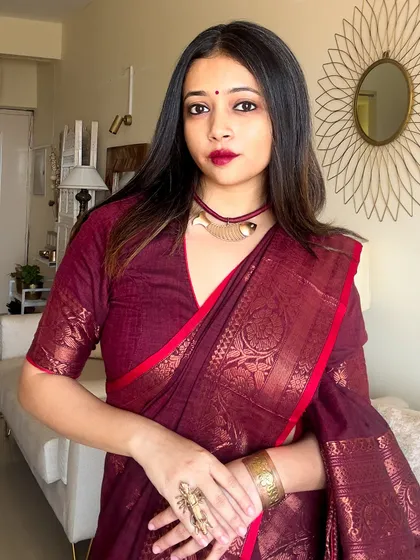 A portrait focusing on the statement copper jewelry against the rich burgundy of the saree. The textures and colors complement each other perfectly.