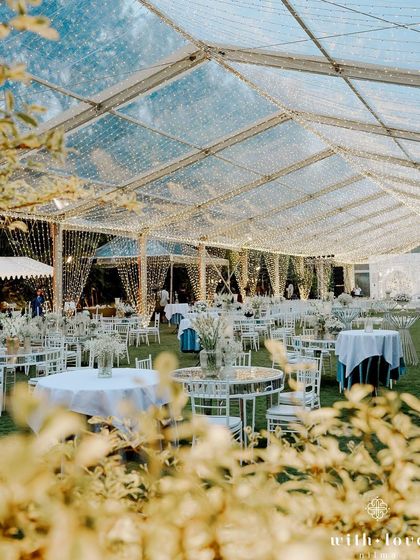 A daytime view of the clear-top tent setup, showing the scale of the event space before the sun sets. The elegant white seating and mirrored tables are ready for the magical night ahead.