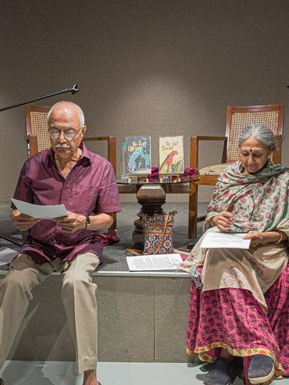 A theatrical reading in progress. Performers sit on stage, bringing a script to life for an attentive audience.