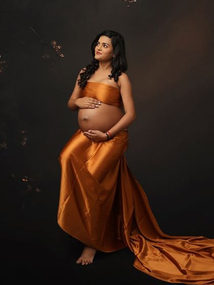 A classic fine art pose, highlighting the baby bump with a beautiful satin drape. The long train adds a touch of drama and elegance to this timeless maternity portrait.
