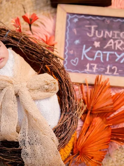 A personalized newborn shot with a chalkboard announcing the baby's name and birth date, nestled in a cozy basket with autumn-colored props.