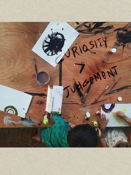 This is the heart of our philosophy: Curiosity over Judgement. In this overhead view of a children's art session, you can see the free exploration and creative expression that we encourage in all our workshops, fostering a safe space for self-discovery without fear of mistakes.