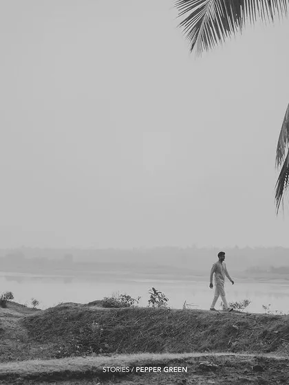 An atmospheric, black and white shot of the groom walking near the serene backwaters. This kind of scene-setting shot adds a cinematic quality to the wedding film.