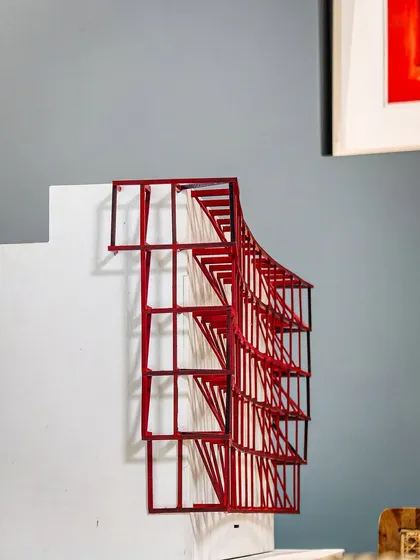 A conceptual study model of a curved metal exoskeleton. This red-painted model was an early exploration of a structural idea for a facade, testing its geometric complexity and visual impact.