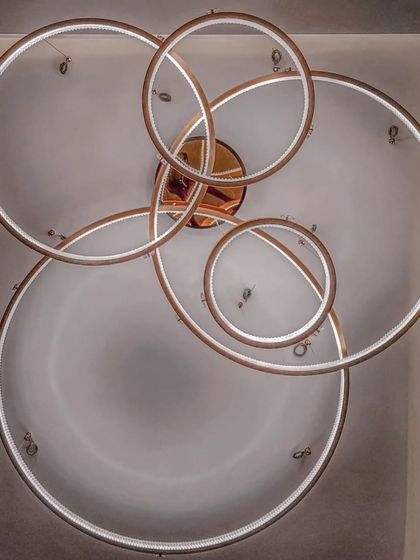 The modern, interlocking ring chandelier in Mr. Sameer's cabin at the Sun Group office. This sculptural light fixture serves as a centerpiece, adding a touch of artistic flair to the corporate space.