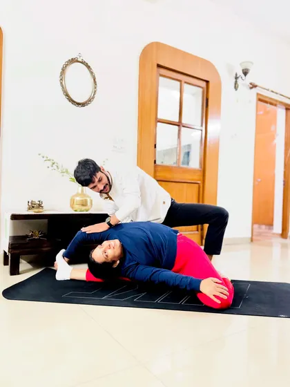 Achieving deep flexibility requires patience, trust, and expert guidance. Here, I am assisting a client in a reclining hero pose variation, focusing on safely opening the hips and shoulders. My hands-on approach ensures you can explore your body's limits without risk of injury, making advanced postures more accessible.