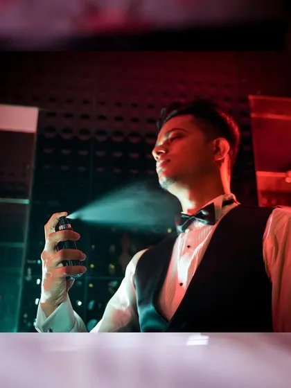 A stylish and creative shot of the groom getting ready for his church wedding. The dramatic lighting and use of spray creates a cool, cinematic portrait.