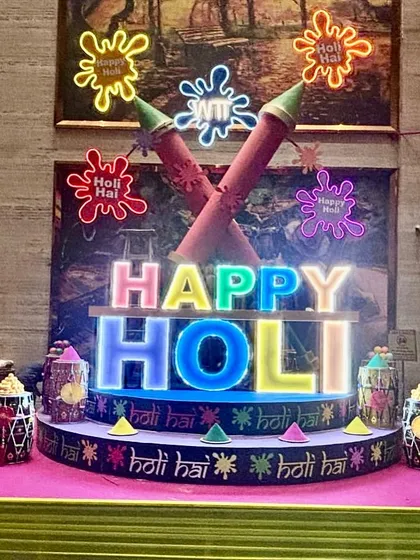 We created this vibrant, large-scale installation for a Holi celebration, featuring custom-lit 'Happy Holi' lettering and oversized pichkari props. This type of illuminated centerpiece becomes the focal point for any festive corporate or private gathering.