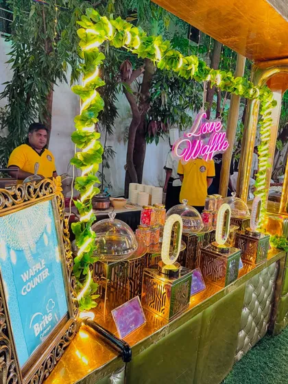 Another view of the waffle station, showcasing the elegant setup with glass cloches and crystal-style lamps.