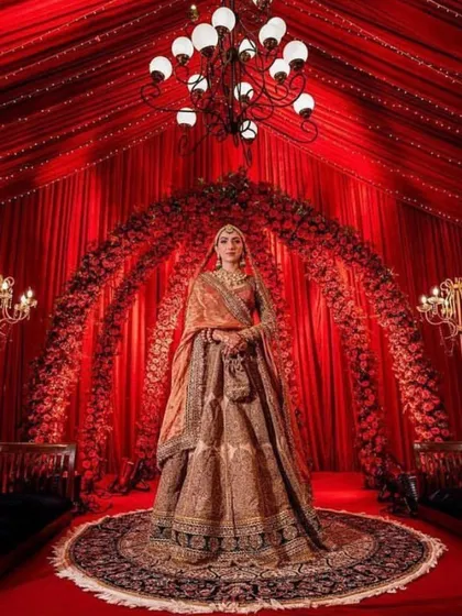 A breathtaking bridal portrait within a royal red themed decor, featuring dramatic draping and a grand floral arch.