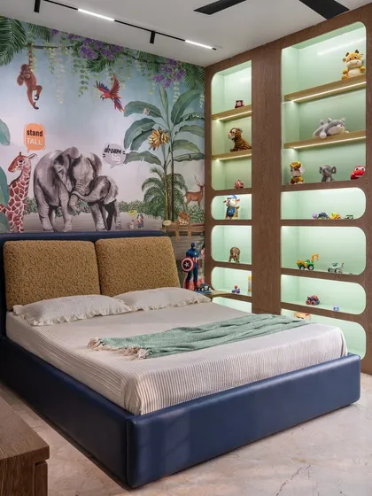 The bed in the jungle room is set against a vibrant wallpaper mural. We also included custom-built, backlit shelving to display a collection of toys, making storage a fun part of the decor.
