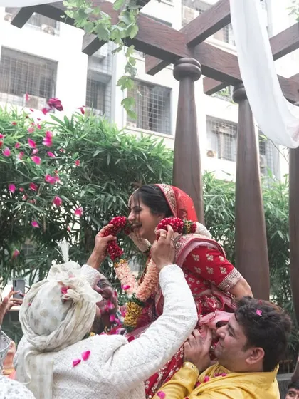 The bride being lifted by her family during the varmala ceremony, a fun and traditional moment of friendly competition.