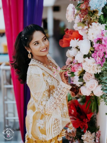 A beautiful portrait of the bride interacting with the floral decor at her vibrant pre-wedding party.