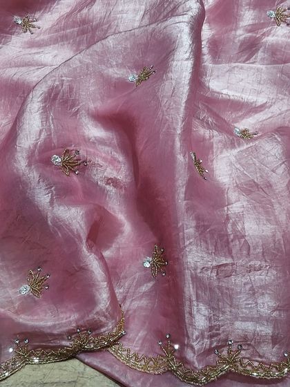 A soft pink crush tissue saree with delicate embroidery. The lightweight and comfortable fabric makes it easy to drape, while the subtle sparkle is perfect for evening events.