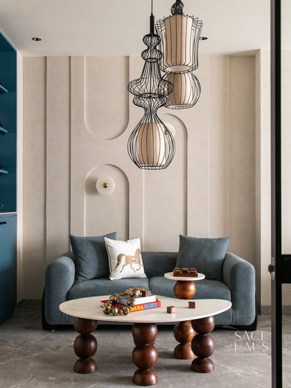 This living space is designed to feel like a work of art. The textured, curved wall accents, sculptural lighting, and a rich blue palette create a room that is both bold and serene, where every element is a study in detail and balance.