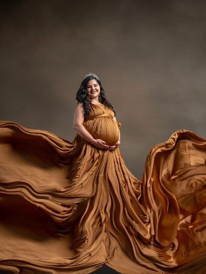 Golden moments and boundless joy as she awaits her little miracle, draped in a magnificent, flowing golden gown that fills the frame.