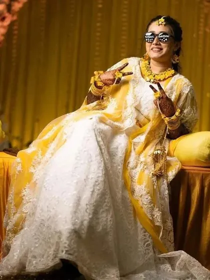 A fun shot of the bride at her haldi ceremony, striking a pose and showing off her full bridal henna.