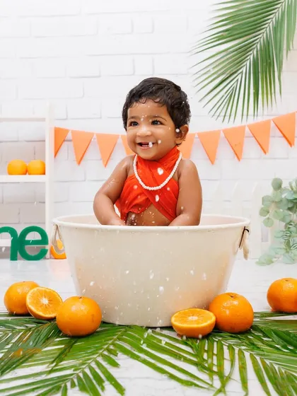 Splish, splash! A baby girl having a blast and making a splash during her fun, orange-themed bath time shoot.