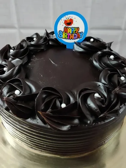 A simple yet delicious chocolate cake with dark chocolate rosettes and a "Happy Birthday" topper.