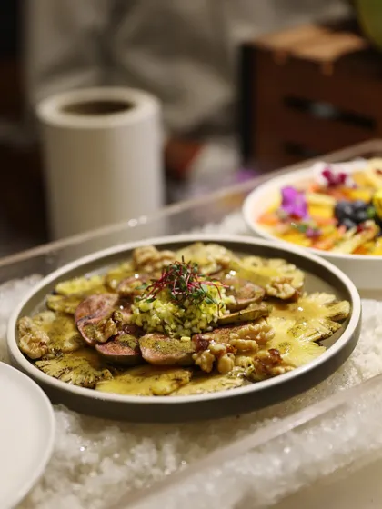 Thinly sliced pineapple carpaccio topped with a zesty gremolata, offering a unique and refreshing twist on a classic dish.