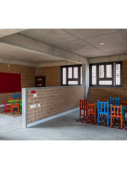 A classroom space at the Mathru Centre. We used low, exposed brick walls to partition the space, creating distinct activity zones without closing off the room entirely. The colorful furniture adds a playful touch.