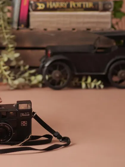 A creative shot from the academic theme, showing the baby's hand reaching for a vintage camera, with books and a toy car in the background.