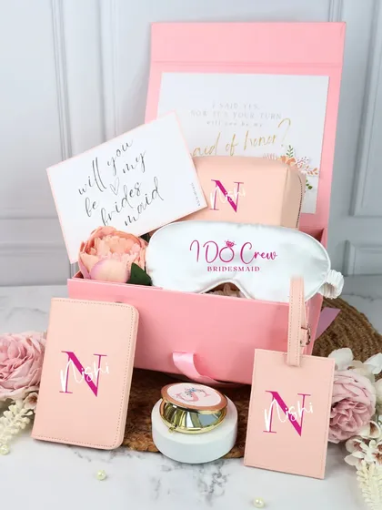 A complete bridesmaid proposal hamper in a soft pink. This gift set comes with a personalized passport cover, luggage tag, "I Do Crew" eye mask, and a custom candle, all packed in a monogrammed box.