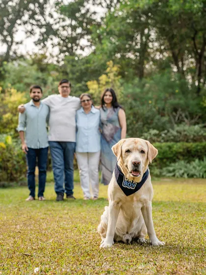 A classic family portrait with a twist. Spike the Labrador sits proudly in the foreground while his loving family stands behind him, showcasing his central role in their lives.