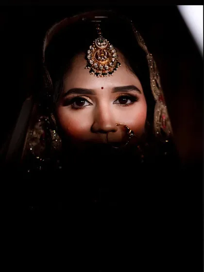 An artistic shot with dramatic shadows, focusing on the bride's mesmerizing eyes and maang tikka.
