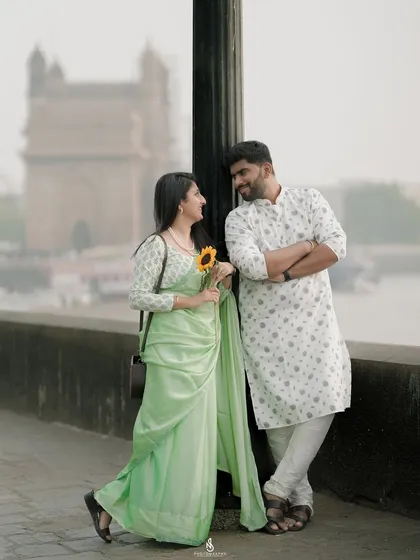 A stylish pose by a lamppost, with the Mumbai harbor as the backdrop. This shot has a classic, timeless feel.