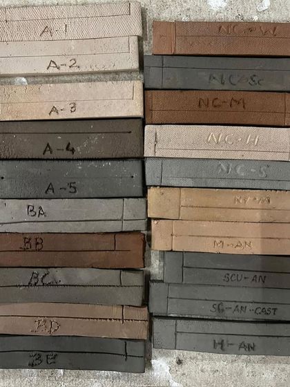 Labeled test tiles for different clay bodies before firing. This systematic approach is crucial for understanding how different materials behave in the kiln.